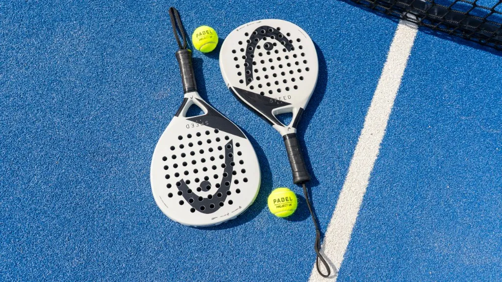 Twee padelrackets en padelballen op een blauwe padelbaan